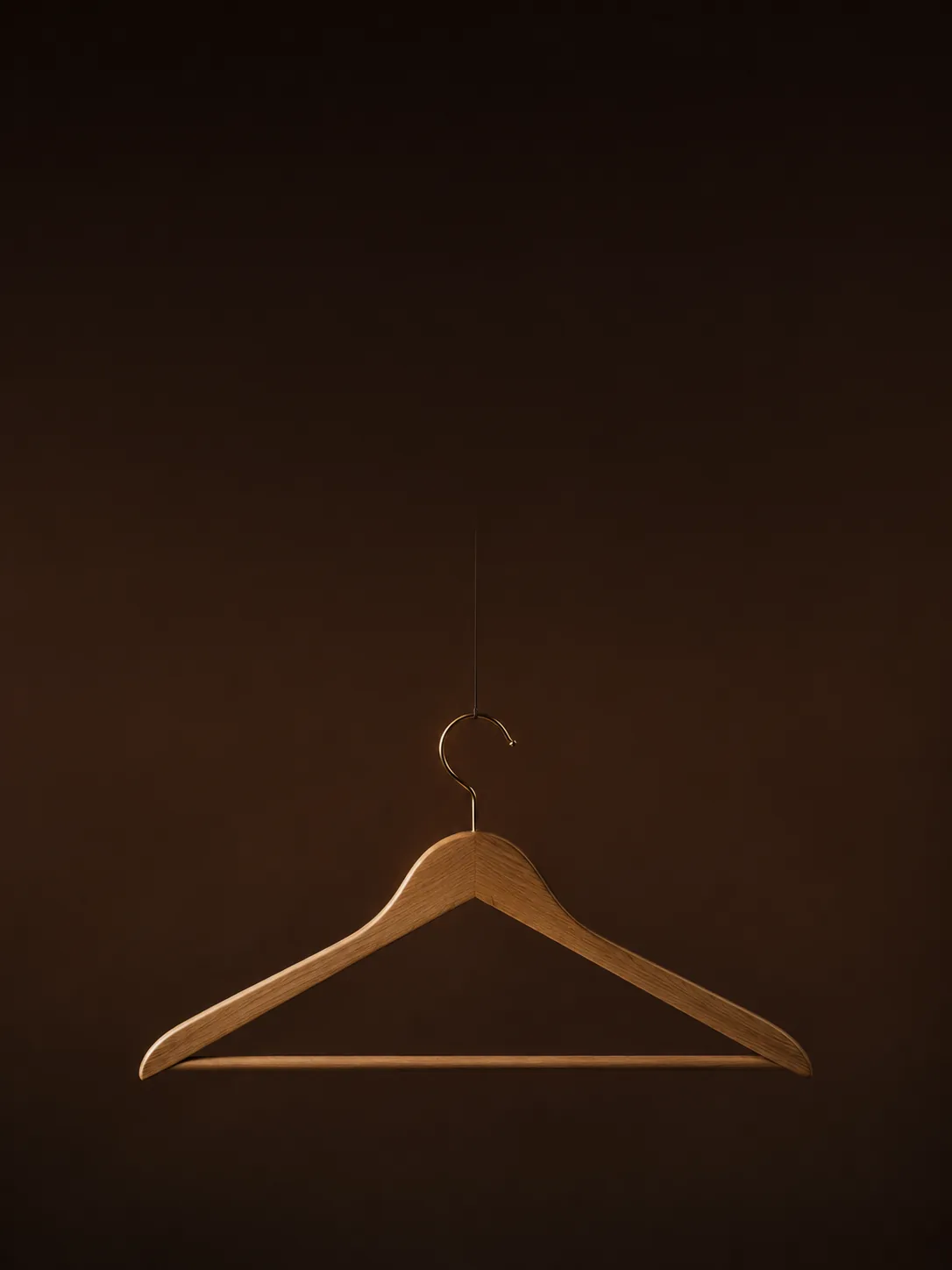 Menos. Mejor. — gancho de madera vacío sobre fondo chocolate
